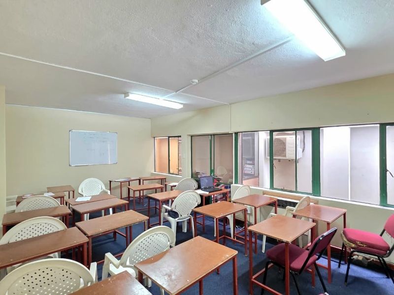 A functional office or classroom space featuring large windows, fluorescent lighting, and a wall-mounted whiteboard, suitable for professional or educational use.