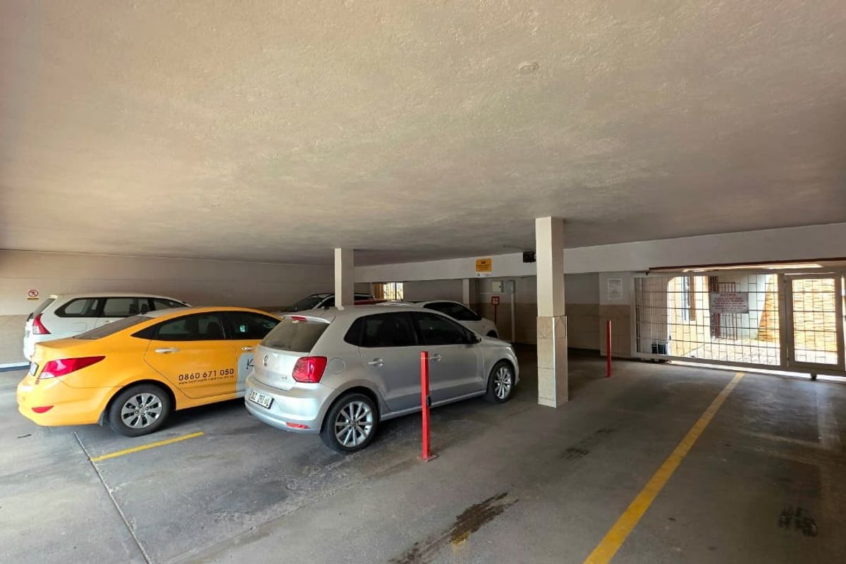 Covered parking garage area featuring concrete flooring, support columns, and a secure gated entrance.