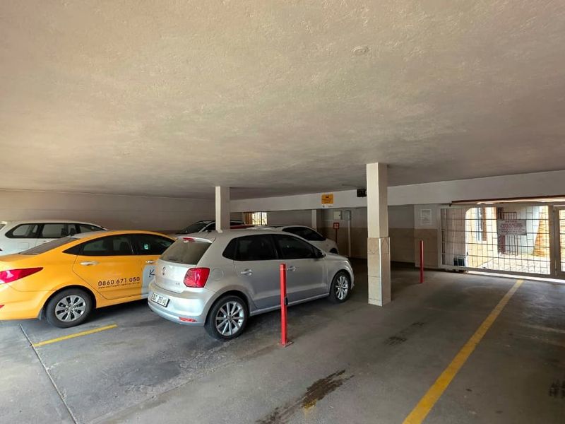 Covered parking garage area featuring concrete flooring, support columns, and a secure gated entrance.