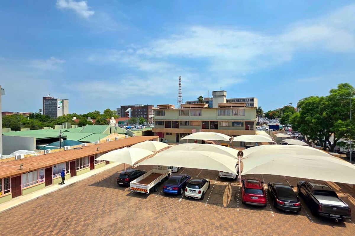 Elevated view of an office property featuring a paved parking lot with shade cloth carports and surrounding commercial building structures.