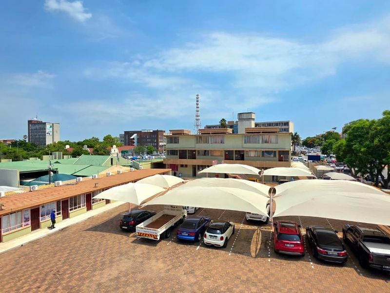 Elevated view of an office property featuring a paved parking lot with shade cloth carports and surrounding commercial building structures.