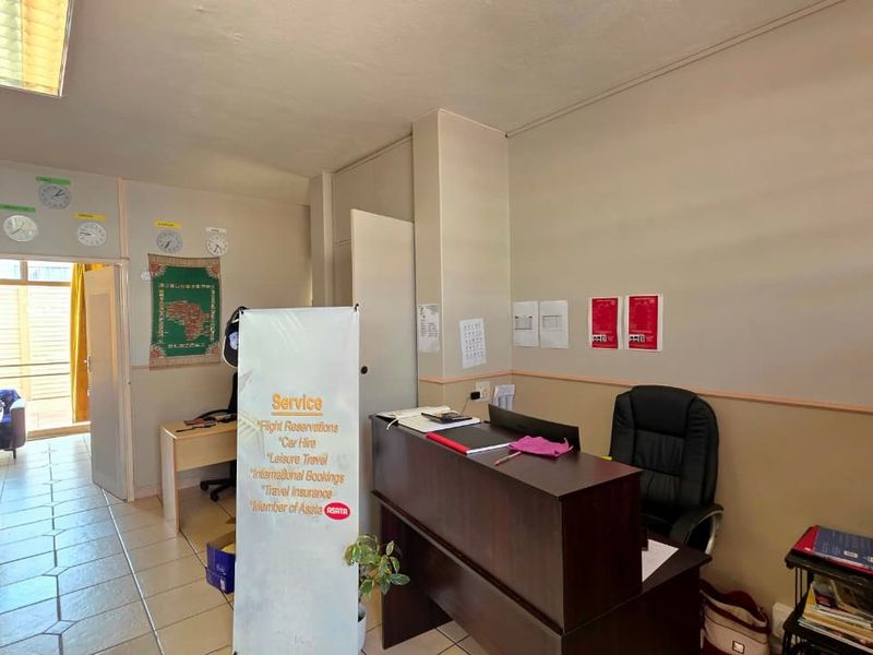 A functional office space featuring tiled flooring, standard fluorescent lighting, and a built-in electrical distribution board, suitable for professional administrative use.