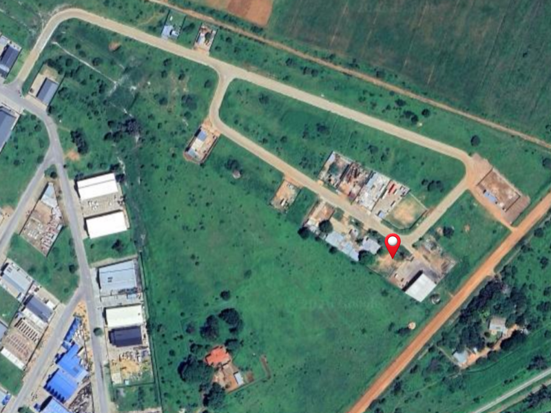 Aerial view of a vacant commercial land plot with access road frontage in a developing industrial area.