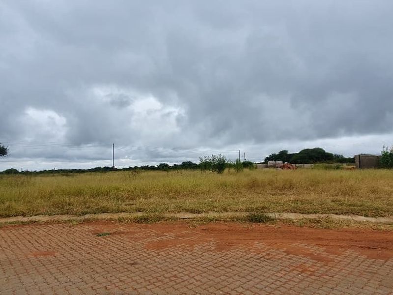 A vacant commercial land plot featuring a paved driveway entrance and perimeter fencing, ready for development.