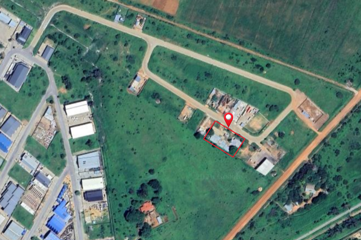 Aerial view of a commercial vacant land plot with road access in a developing industrial or commercial area.