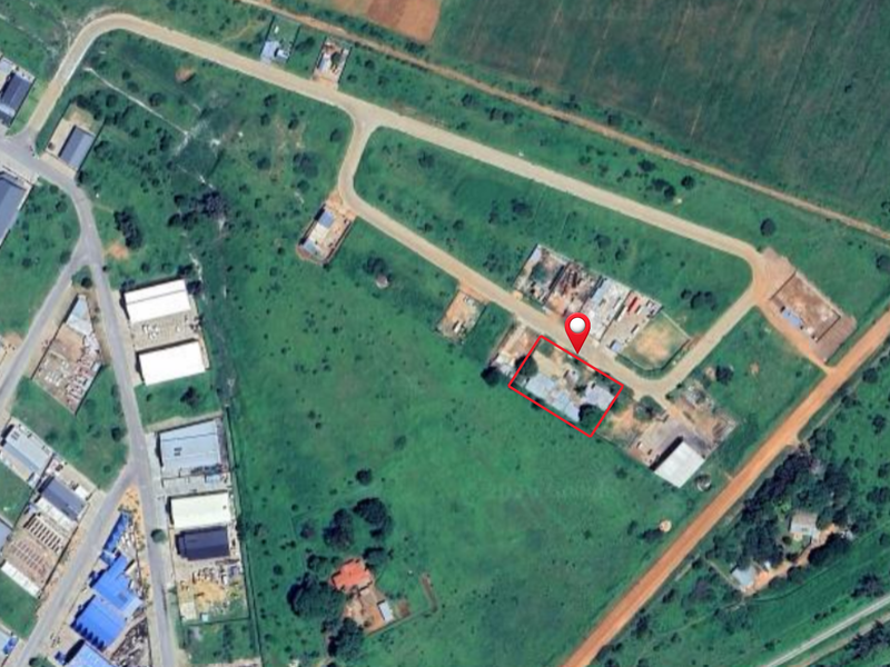Aerial view of a commercial vacant land plot with road access in a developing industrial or commercial area.