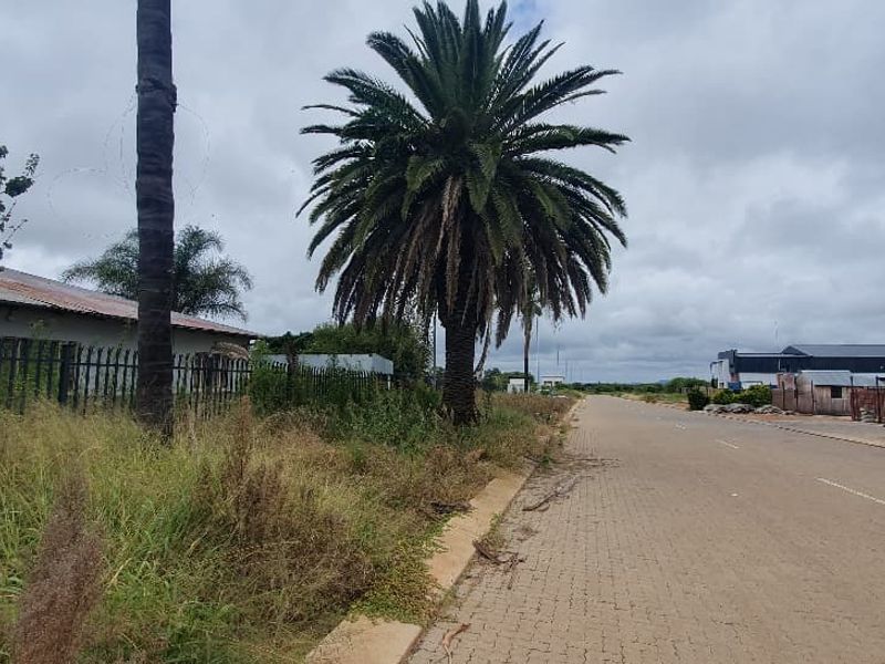 Street view of the commercial property showing paved road access, metal palisade fencing, and established landscaping.