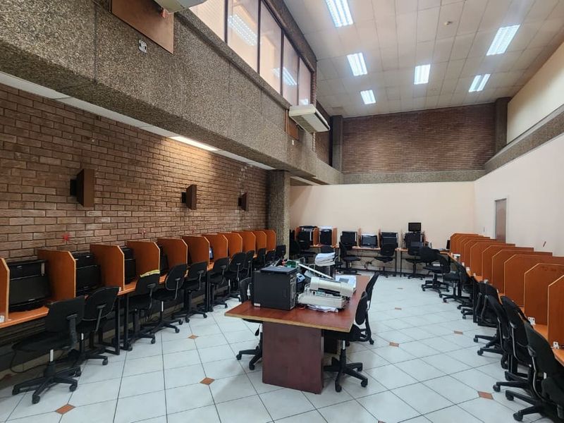 Spacious office area featuring multiple built-in workstation partitions, exposed brick walls, and a suspended ceiling with integrated lighting.
