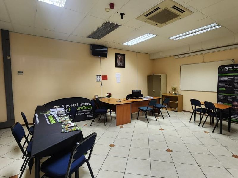 A functional office space featuring ceramic tiled flooring, a suspended ceiling with recessed lighting, integrated air conditioning, and a wall-mounted whiteboard.