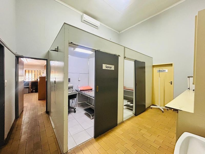 Commercial medical utility space featuring partitioned examination cubicles, split-system air conditioning, and functional tiled flooring.