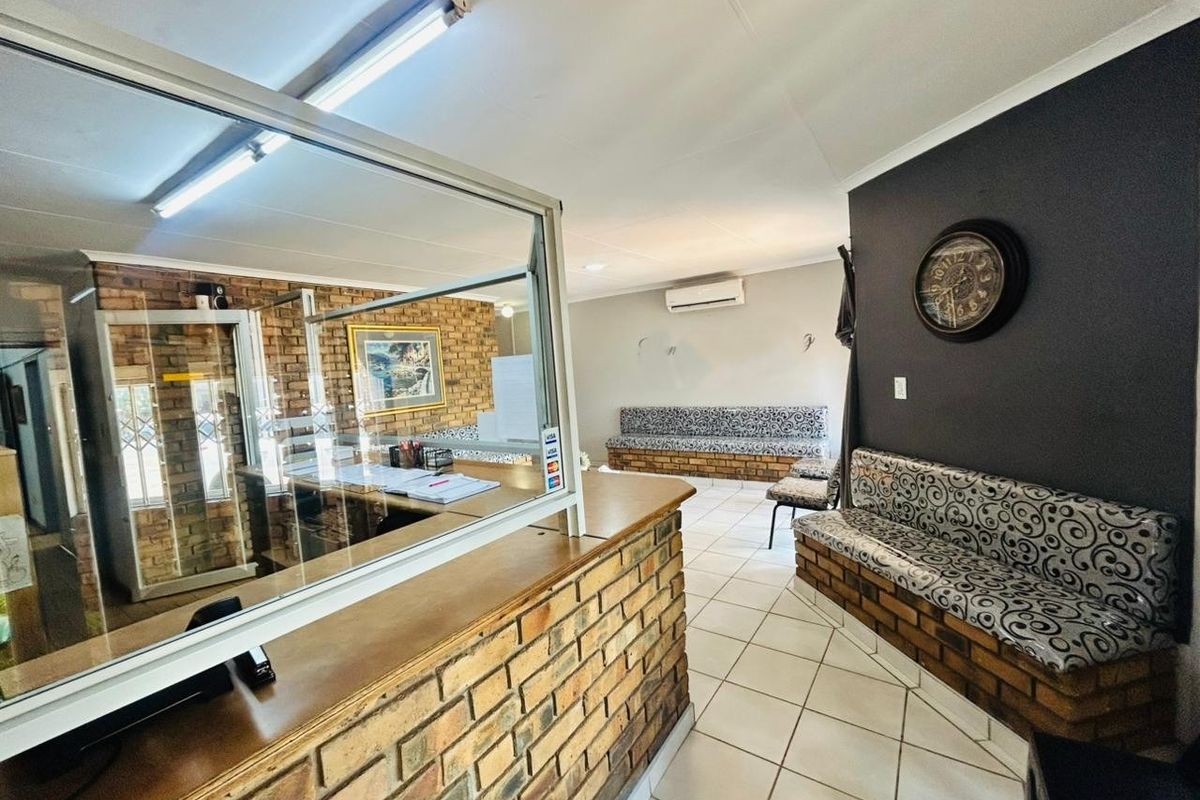 Commercial reception area featuring a brick counter with a glass security screen, built-in brick bench seating, and tiled flooring.