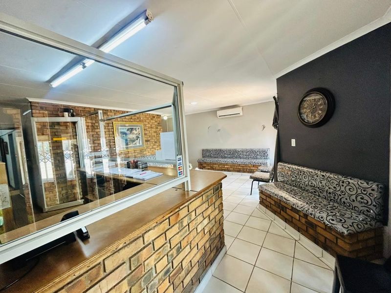 Commercial reception area featuring a brick counter with a glass security screen, built-in brick bench seating, and tiled flooring.