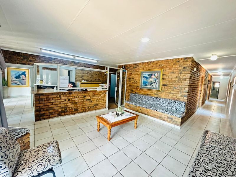 Commercial reception area featuring a brick feature wall, built-in reception desk, integrated bench seating, and ceramic tile flooring.