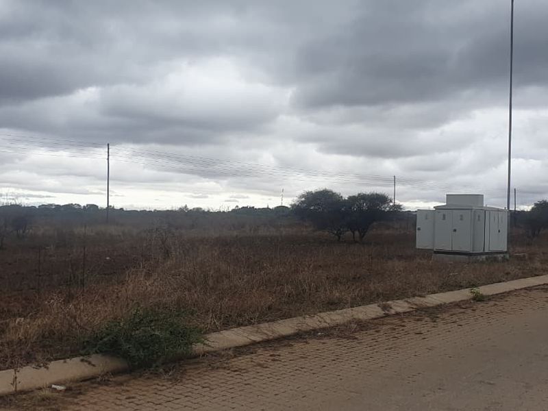 A view of a vacant commercial land plot featuring a paved curb and an electrical utility box situated along the roadside.