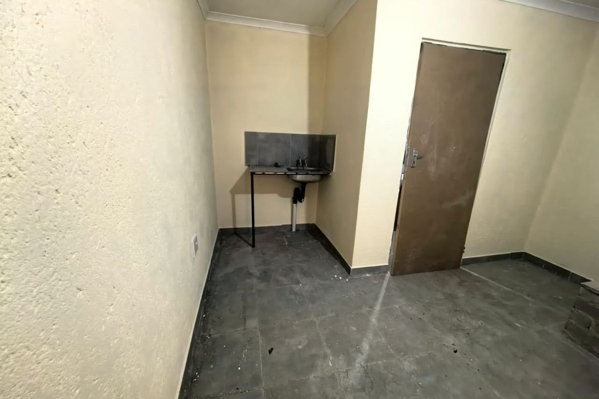 A small, basic kitchen area featuring a single sink, tiled splashback, and tiled flooring, currently in need of cosmetic updates and maintenance.