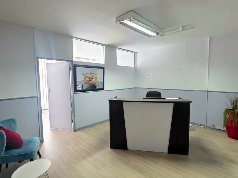 A functional office space featuring laminate flooring, neutral wall finishes, and overhead fluorescent lighting, suitable for a professional reception or workspace area.