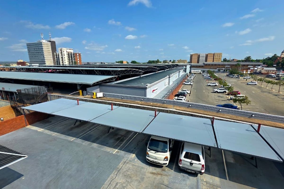Aerial view of an office property featuring extensive covered parking bays, paved surfaces, and large-scale industrial-style roofing structures.