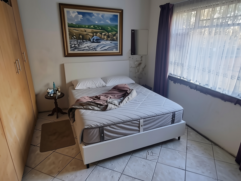 A bedroom featuring built-in wooden cupboards, tiled flooring, and a large window allowing natural light into the space.