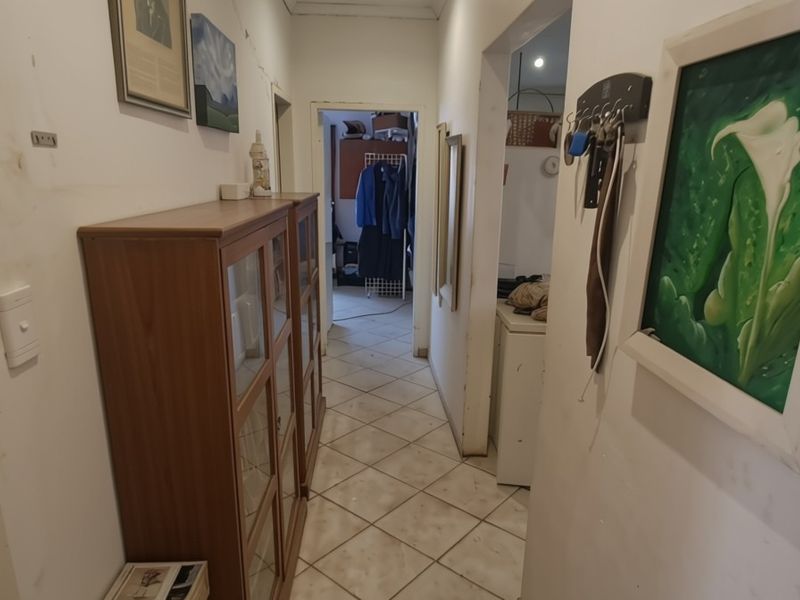 A narrow interior hallway featuring tiled flooring and access to adjacent rooms, showing signs of wear on the wall surfaces.
