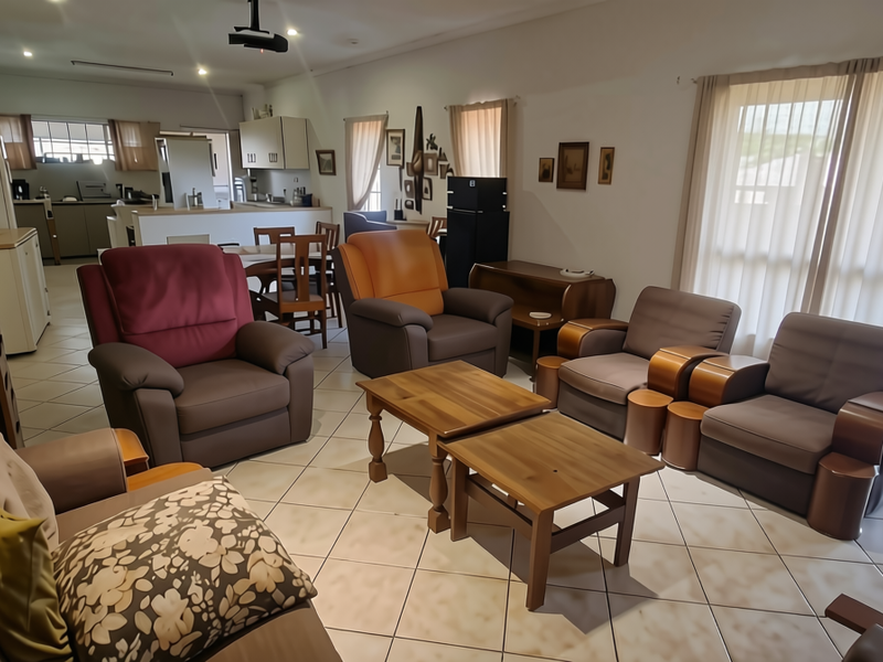 Spacious open-plan living and kitchen area featuring ceramic tile flooring, recessed lighting, and large sliding glass doors leading to an outdoor patio.