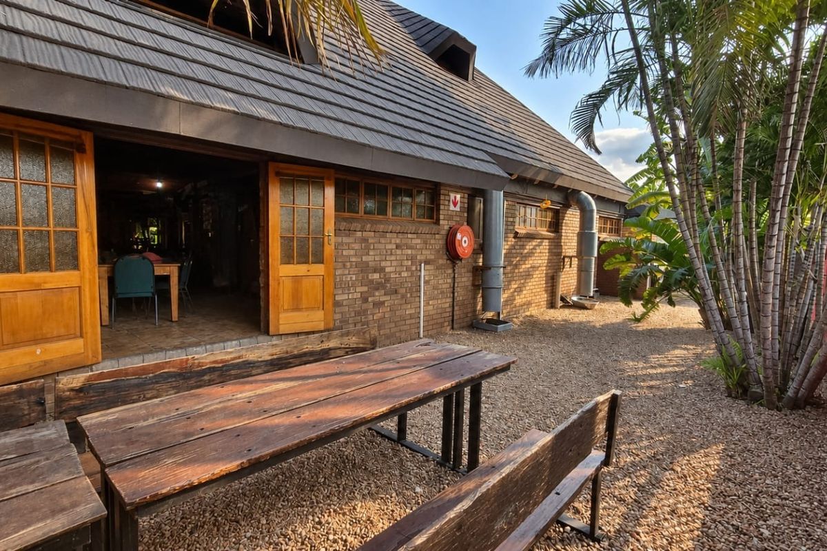 Rear exterior view of a brick building featuring a tiled roof, timber-framed doors, and external ventilation infrastructure, set within a gravel courtyard area.