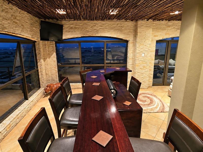 A well-appointed bar area featuring unique twig ceiling detailing, stacked stone walls, and expansive windows offering panoramic views.