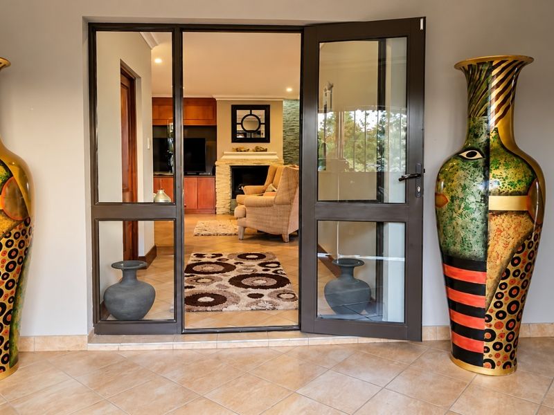 Entrance area featuring an aluminium framed glass door leading into a living space with a built-in fireplace and tiled flooring.