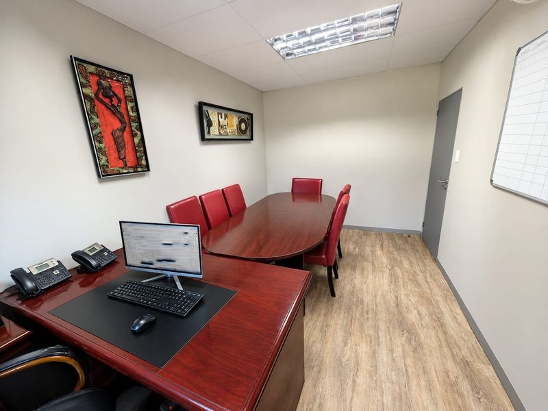 A functional office space featuring laminate flooring, a suspended ceiling with recessed lighting, and a professional layout suitable for meetings or administrative work.