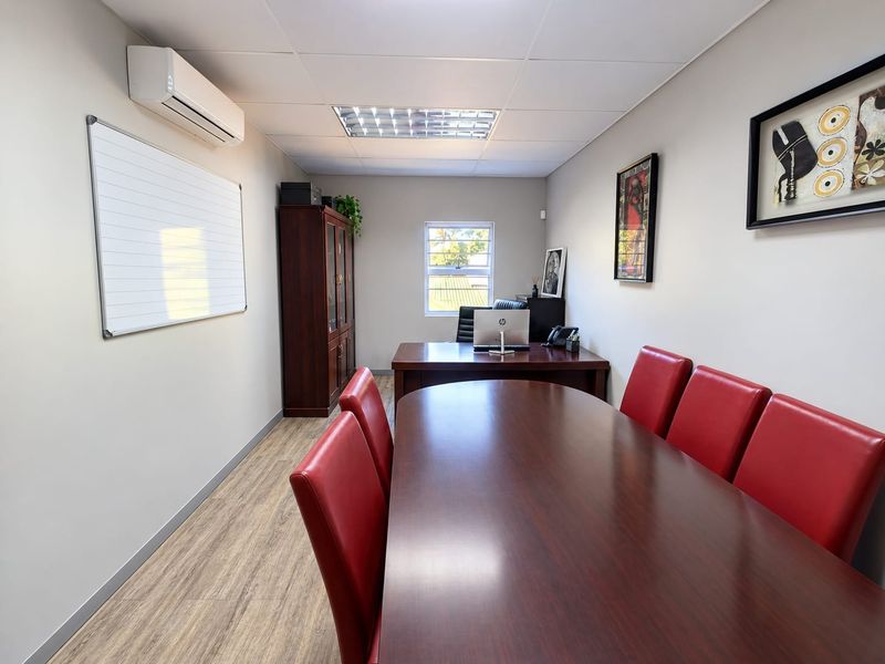 A professional office space featuring laminate wood flooring, recessed lighting, and a wall-mounted split-system air conditioner.