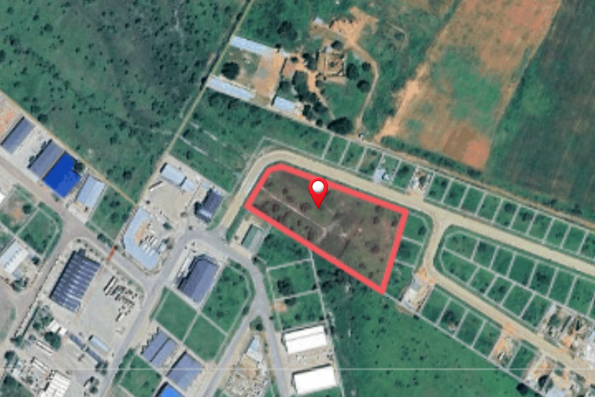 Aerial view of a vacant commercial land plot with road access, situated within a developed industrial or commercial estate.