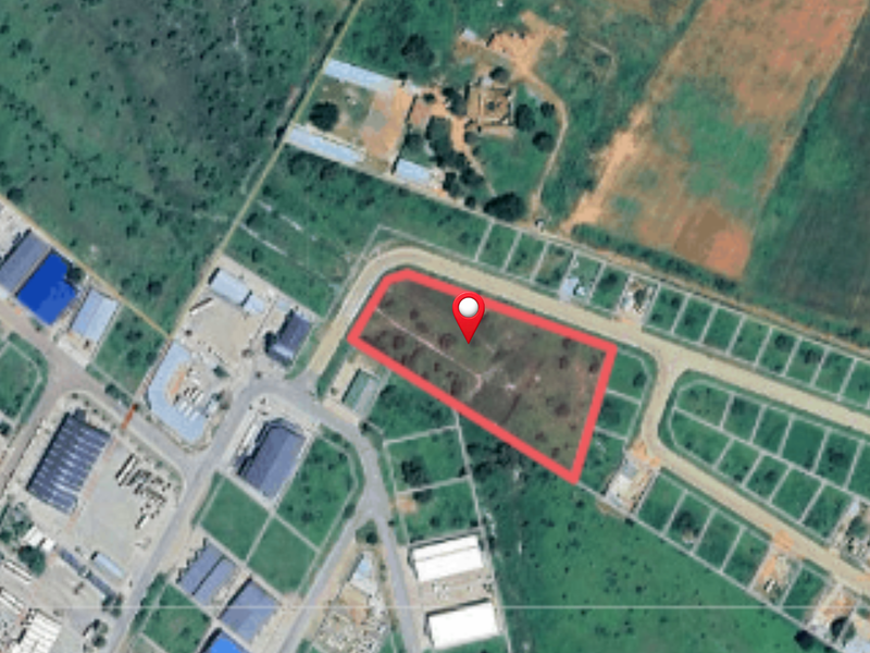 Aerial view of a vacant commercial land plot with road access, situated within a developed industrial or commercial estate.