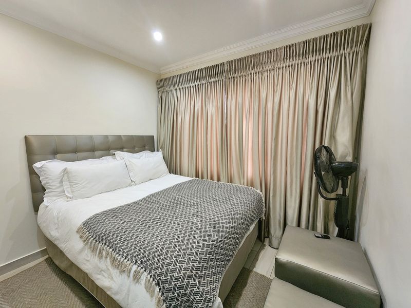A well-maintained bedroom featuring neutral walls, recessed ceiling lighting, and full-length curtains.
