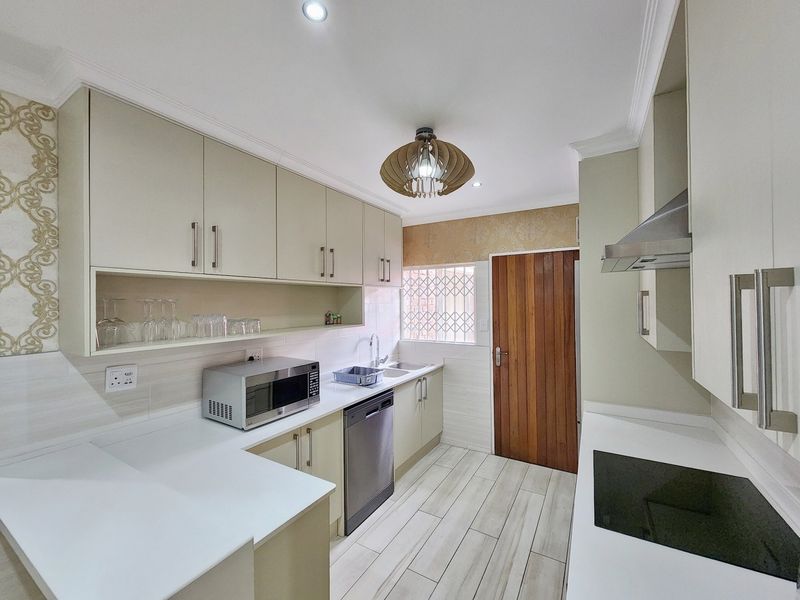Modern kitchen featuring sleek built-in cabinetry, quartz countertops, integrated hob, extractor fan, and tiled flooring with a functional layout.