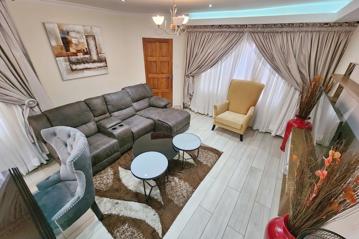 A well-maintained living room featuring tiled flooring, recessed downlighting, and cove lighting, creating a bright and comfortable atmosphere.