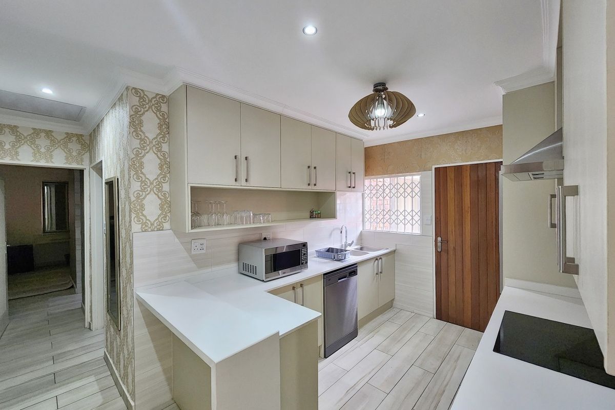 Modern kitchen featuring sleek cabinetry, quartz countertops, integrated hob, extractor fan, and tiled flooring with a clean, functional layout.
