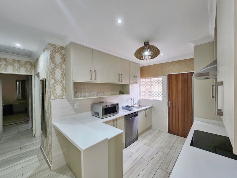 Modern kitchen featuring sleek cabinetry, quartz countertops, integrated hob, extractor fan, and tiled flooring with a clean, functional layout.