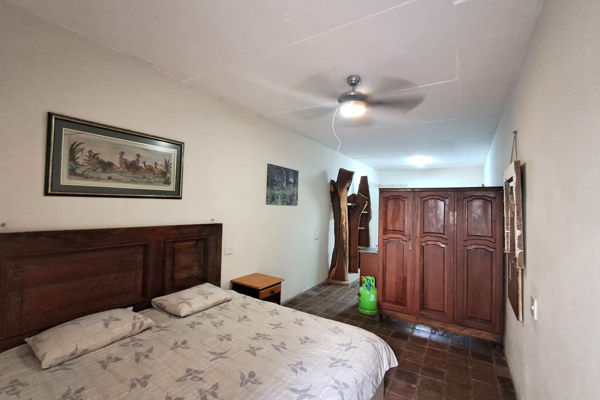 A bedroom featuring tiled flooring, a ceiling fan, and built-in wooden cupboards, requiring some cosmetic updates to improve the overall finish.