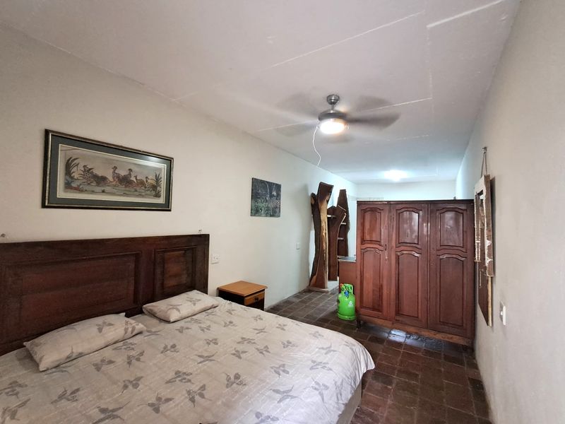 A bedroom featuring tiled flooring, a ceiling fan, and built-in wooden cupboards, requiring some cosmetic updates to improve the overall finish.