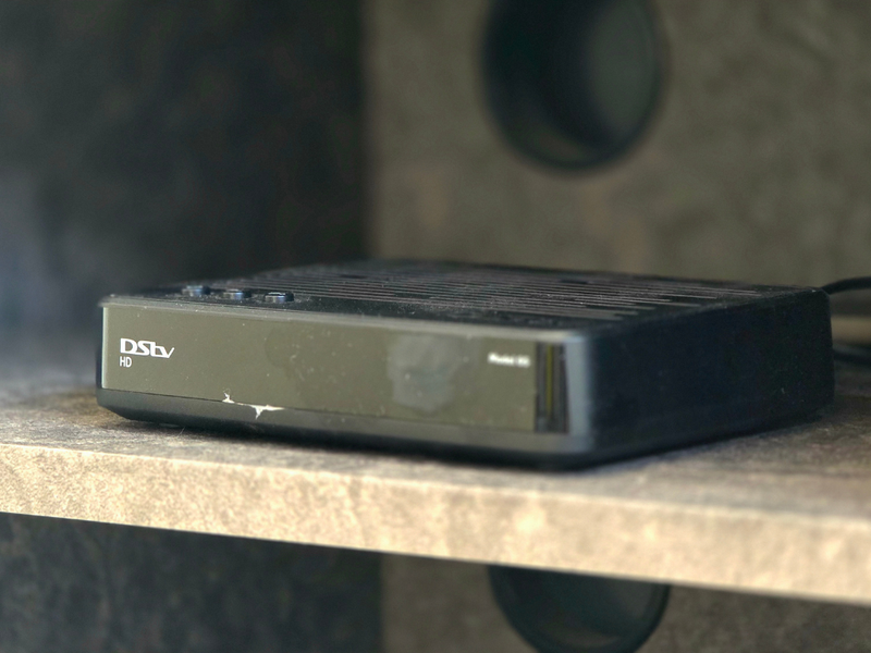 A close-up shot of a DStv decoder unit placed on a shelf.