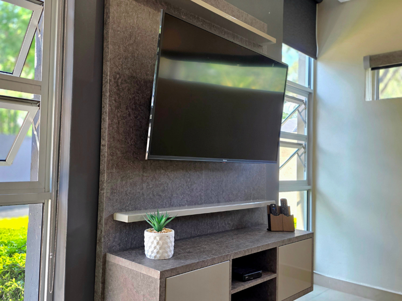 A modern living area featuring a custom built-in media unit with integrated shelving and large louver windows providing natural light.