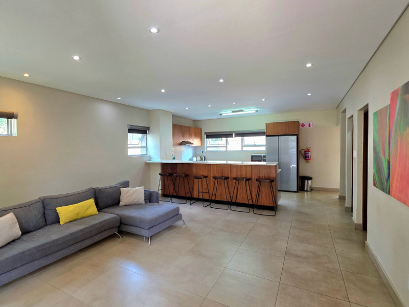 Spacious open-plan living area featuring a modern kitchen with a breakfast bar, tiled flooring, and recessed downlighting throughout the combined space.
