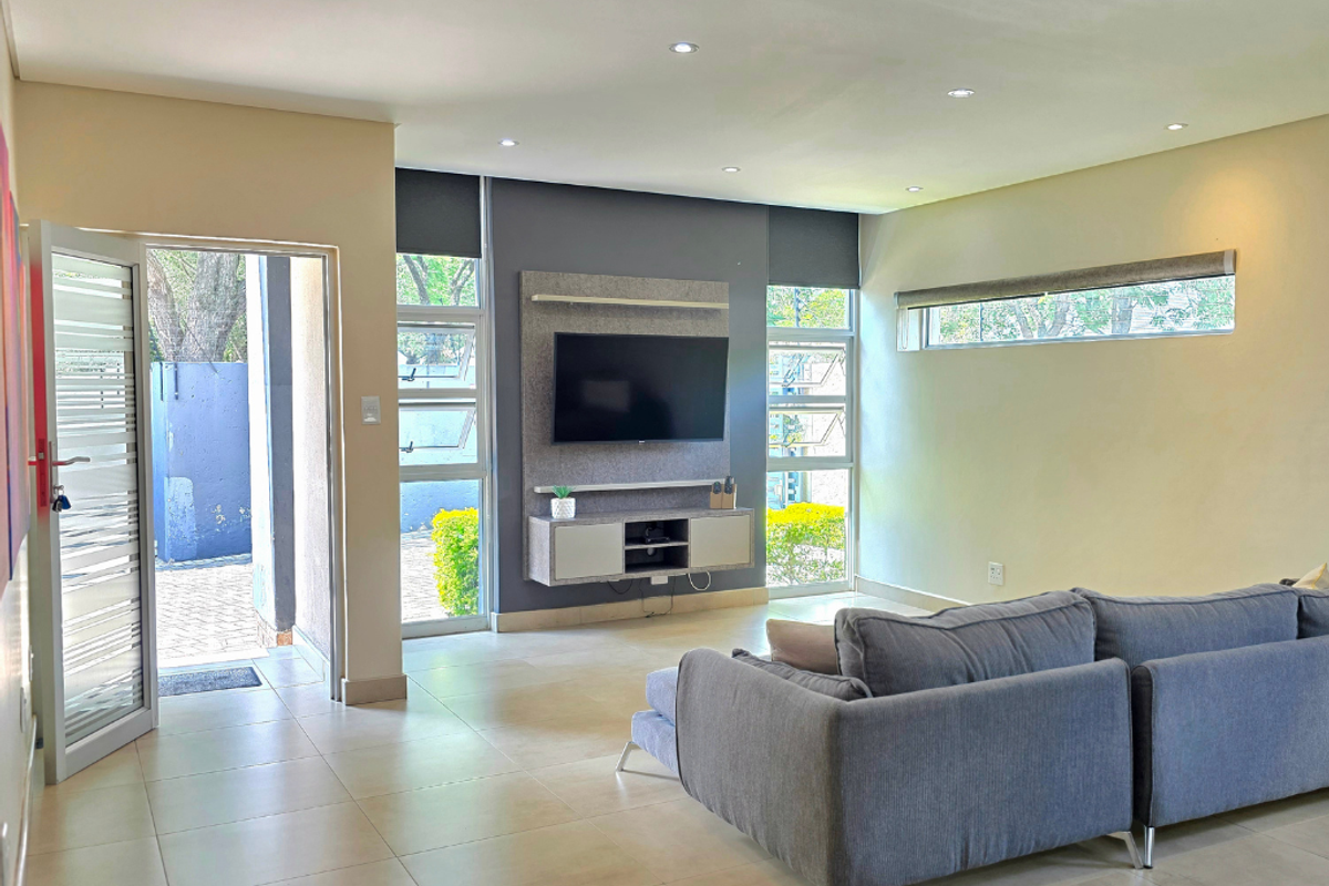 Modern living room featuring tiled floors, recessed lighting, built-in media cabinetry, and direct access to an outdoor area through a security door.
