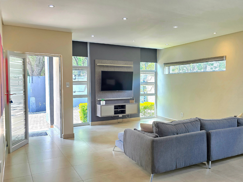 Modern living room featuring tiled floors, recessed lighting, built-in media cabinetry, and direct access to an outdoor area through a security door.
