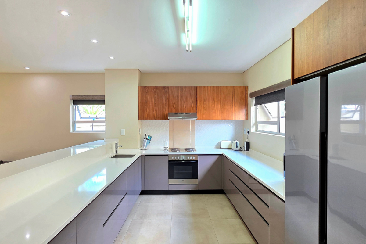 Modern kitchen featuring sleek cabinetry, quartz countertops, integrated oven and hob, and ample workspace with recessed lighting.