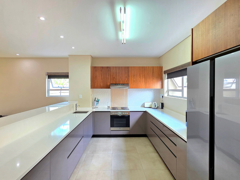 Modern kitchen featuring sleek cabinetry, quartz countertops, integrated oven and hob, and ample workspace with recessed lighting.