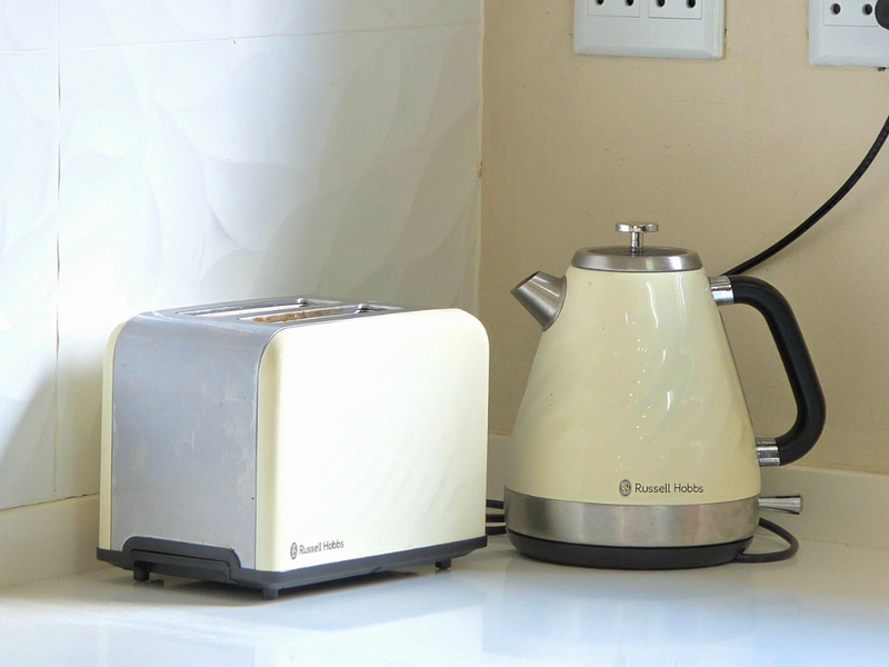A close-up view of a kitchen countertop featuring a tiled backsplash and electrical outlets.