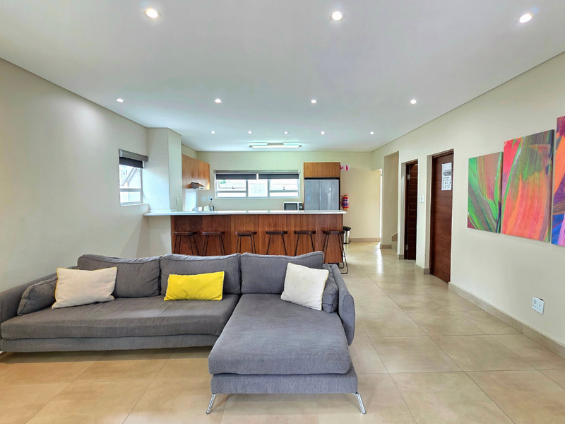 Spacious open-plan living area featuring tiled floors, recessed lighting, and a modern kitchen with a breakfast bar and wooden cabinetry.