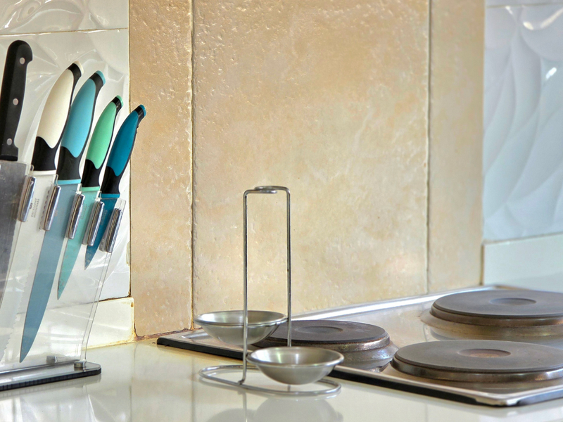 Close-up view of a kitchen workspace featuring an electric hob and decorative tiled splashback.