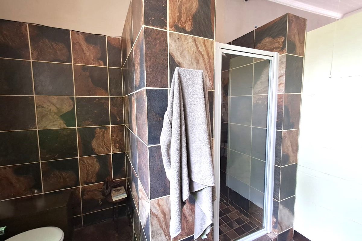 Bathroom featuring a shower enclosure with dark decorative wall tiles and a standard toilet.