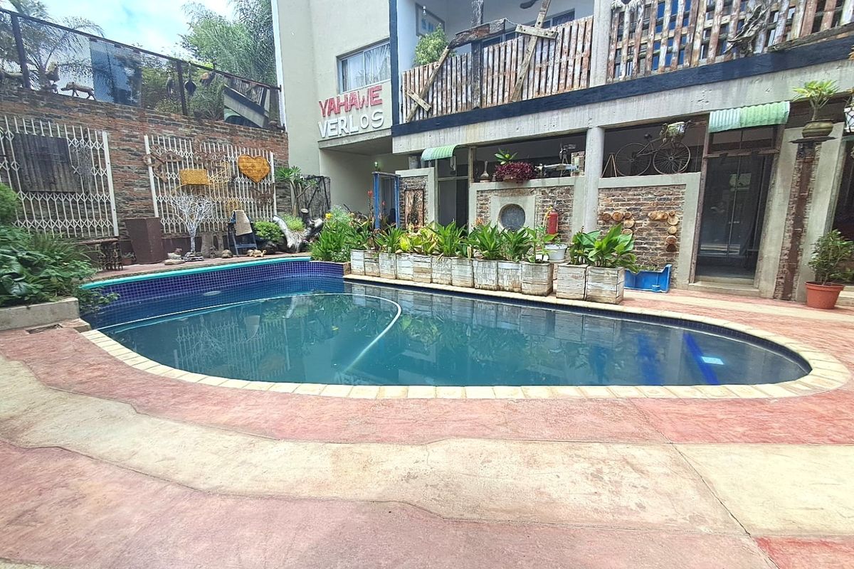 Outdoor pool area featuring a curved swimming pool with a tiled surround, set against a multi-level building facade with brick and concrete elements.